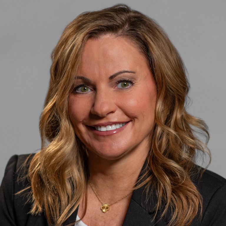 Professional woman with wavy blonde hair smiling warmly.